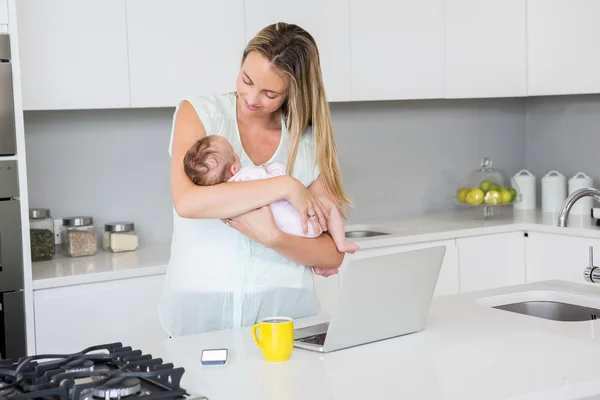 Mother carrying her baby in kitchen — Stock Photo, Image