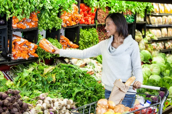 Frau kauft Möhre in Bio-Abteilung — Stockfoto