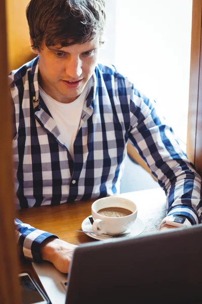 Estudiante usando el ordenador portátil mientras toma café — Foto de Stock