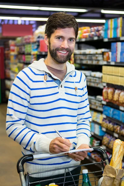Человек пишет на блокноте во время покупок — стоковое фото