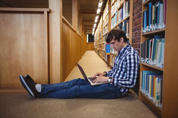 Uczeń korzysta z laptopa w bibliotece — Zdjęcie stockowe