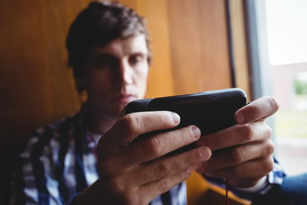 Student met behulp van mobiele telefoon in de buurt van venster — Stockfoto