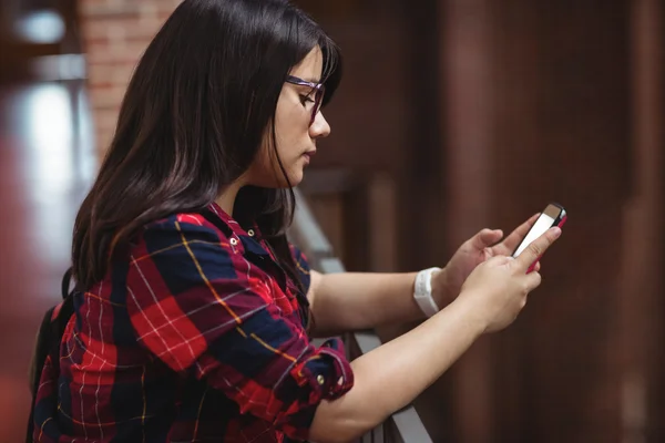 Vrouwelijke student met behulp van telefoon in gang — Stockfoto