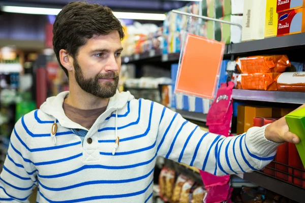 Homme sélectionnant un produit d'épicerie dans une étagère — Photo