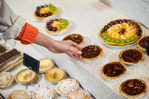 Woman selecting tart from display — Stock Photo, Image