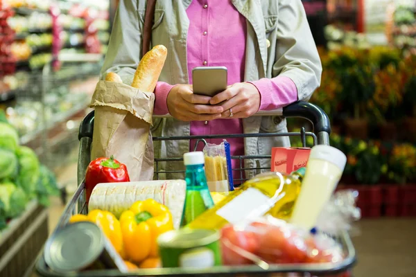 Mujer usando el teléfono durante las compras — Foto de Stock