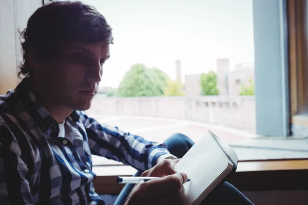 Student skriver anteckningar nära fönster — Stockfoto