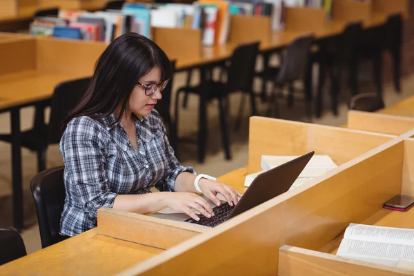 Estudante feminina usando laptop na biblioteca — Fotografia de Stock