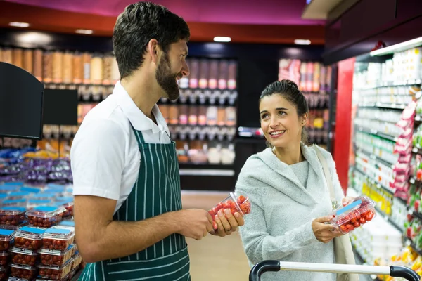 Personal masculino sonriente ayudando a una mujer con compras de comestibles —  Fotos de Stock