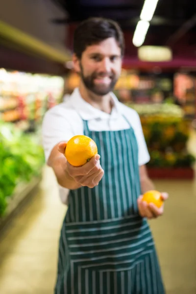 Lächelnde männliche Mitarbeiter zeigen Obst in Bio-Supermarkt — Stockfoto