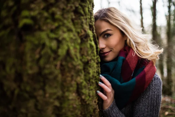 Kvinna gömmer sig bakom trädstammen — Stockfoto