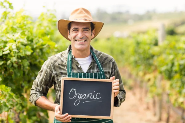 Agricultor sorridente segurando um sinal biológico — Fotografia de Stock