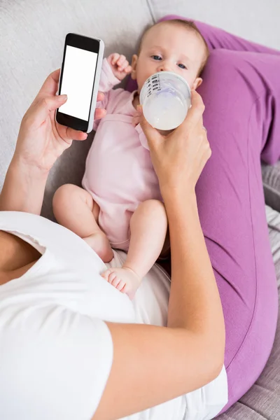 Mãe usando telefone enquanto alimenta o bebê — Fotografia de Stock