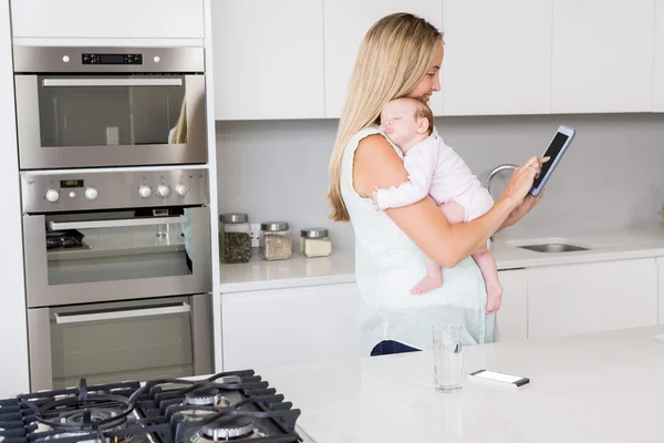 Madre che utilizza tablet durante il trasporto del bambino — Foto Stock