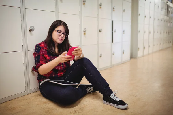 Female student using phone in locker room — Stock Photo, Image