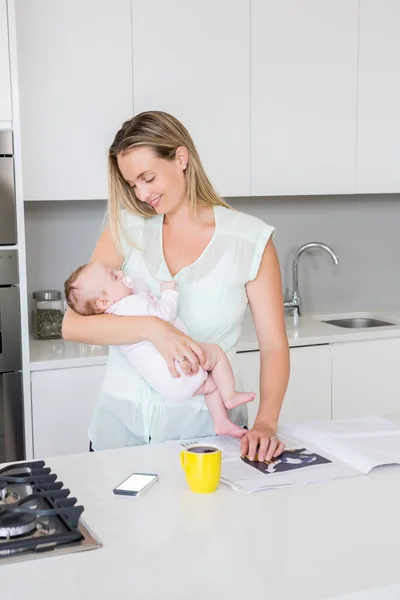 Mãe carregando seu bebê na cozinha — Fotografia de Stock