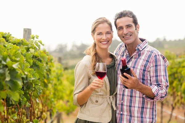 Pareja sosteniendo un vaso y una botella de vino —  Fotos de Stock