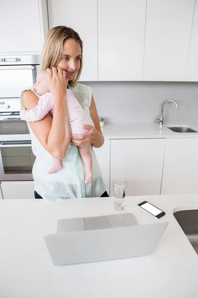 Mother carrying her baby in kitchen — Stock Photo, Image