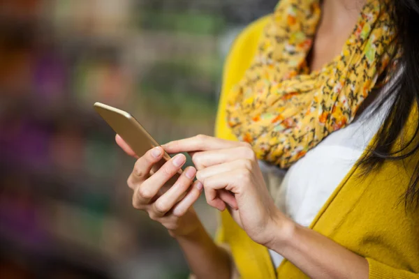Vrouw met telefoon in supermarkt sectie — Stockfoto