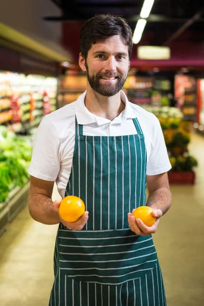 Personal masculino sonriente sosteniendo fruta en la sección orgánica del supermercado —  Fotos de Stock