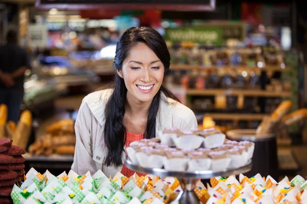 Femme heureuse regardant des cupcakes — Photo