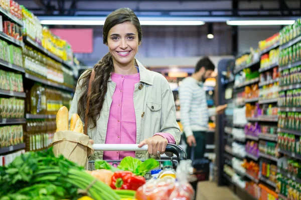 Kobieta z warzywami w wózek na zakupy — Zdjęcie stockowe