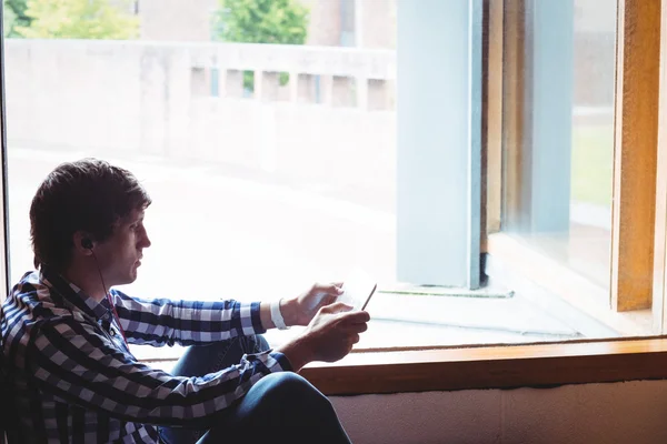 Φοιτητής χρησιμοποιώντας ψηφιακή δισκίο κοντά σε παράθυρο — Φωτογραφία Αρχείου