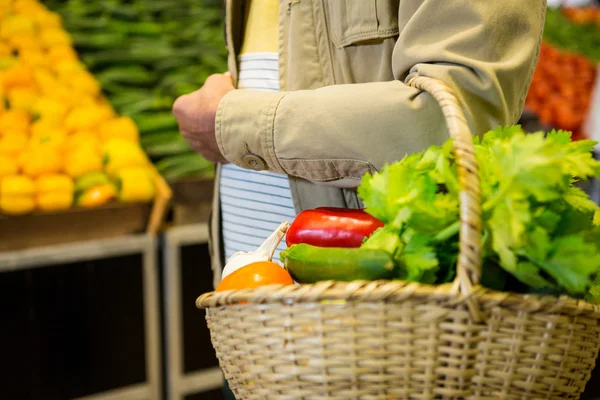 Hombre sosteniendo una cesta de verduras en el supermercado —  Fotos de Stock