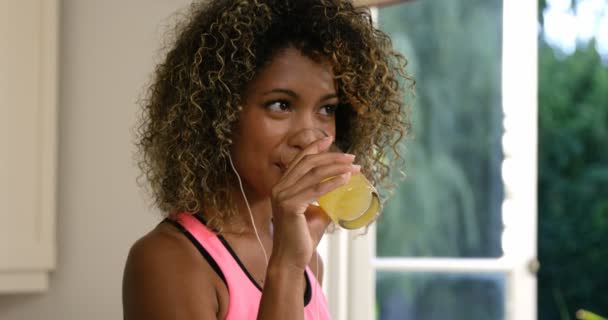 Woman drinking juice while listening to music — ストック動画