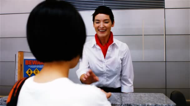 Female airport staff checking passport with woman — Stockvideo