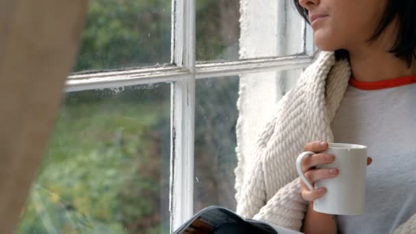 Женщина сидит на подоконнике и пьет кофе — стоковое видео