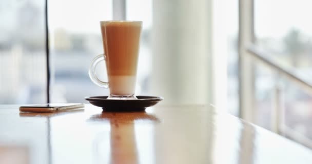 Glas koffie en mobiele telefoon op tafel — Stockvideo