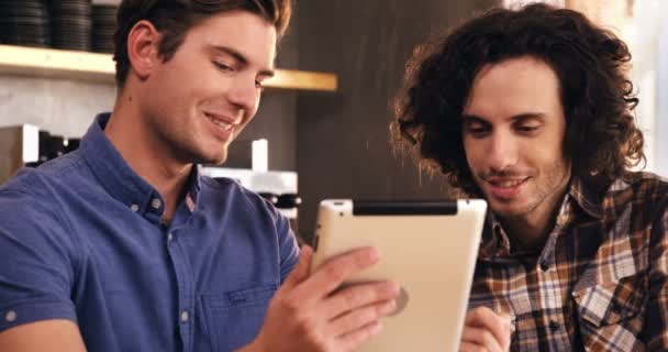 Δύο άνδρες χρησιμοποιώντας ψηφιακό tablet σε καφετέρια — Αρχείο Βίντεο