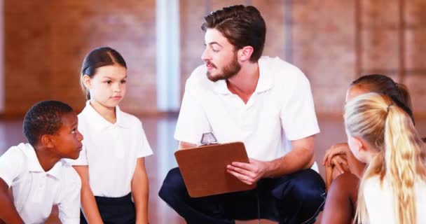 Sports teacher and school kids stacking hands — Stockvideo