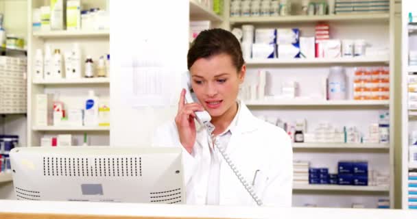 Farmacéutico en el mostrador y hablando por teléfono — Vídeo de stock