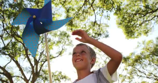 Niño jugando con el molinete en el parque — Vídeo de stock