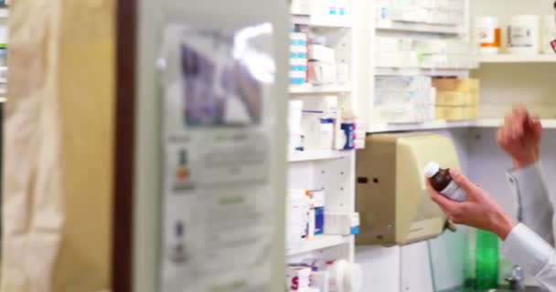 Фармацевт проверяет бутылку лекарства в аптеке — стоковое видео