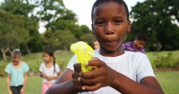 Lachende jongen spelen met water gun automatische waterpistool — Stockvideo