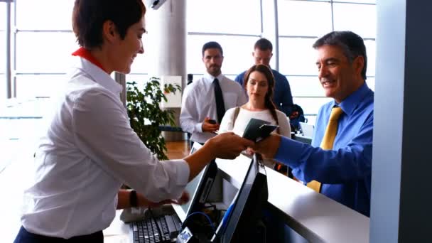 Female airport staff checking passport of commuters at check-in desk — Αρχείο Βίντεο