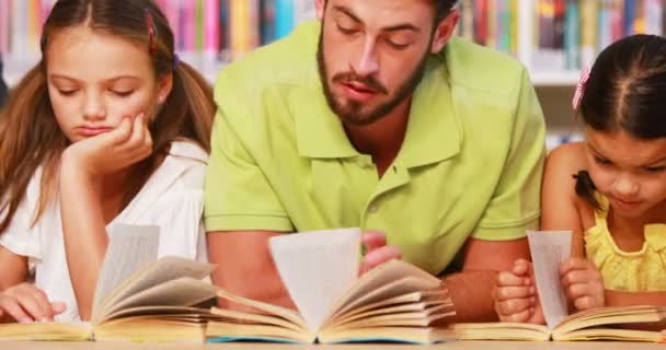 Profesor y niños leyendo libro en la biblioteca — Vídeo de stock