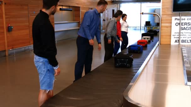 Commuters taking baggage from baggage carousel — Stockvideo