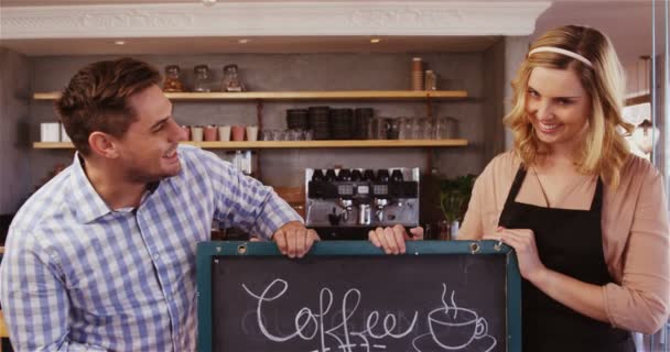 Официантка и мужчина стоят с кофейной вывеской — стоковое видео