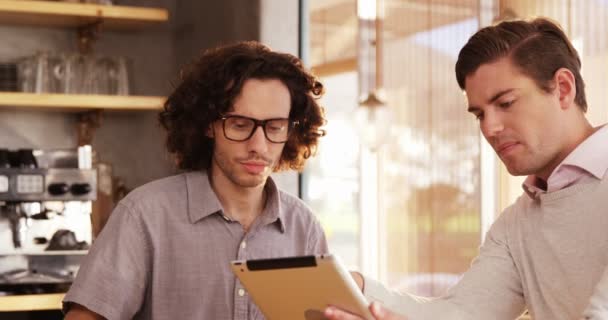 Twee mannen met behulp van digitale tablet in café — Stockvideo