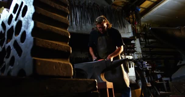 Herrero trabajando en una barra de hierro — Vídeos de Stock