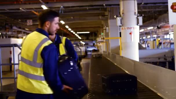 Trabalhador aeroportuário colocando bagagem no carrossel de bagagem — Vídeo de Stock