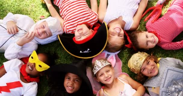 Kinder in verschiedenen Kostümen liegen auf Gras — Stockvideo