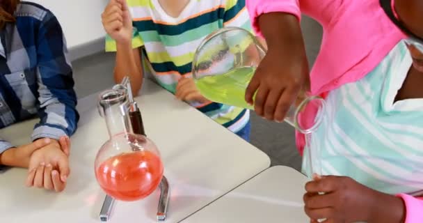 Teacher assisting kids in chemical experiment — ストック動画