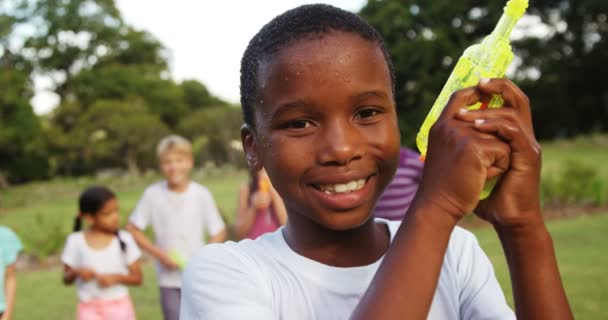 Lachende jongen spelen met water gun automatische waterpistool — Stockvideo