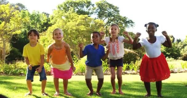 Група дітей, які стрибають разом у парку — стокове відео