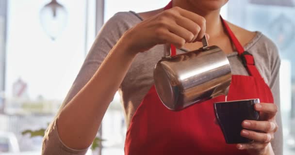Официантка наливает молоко в чашку кофе — стоковое видео